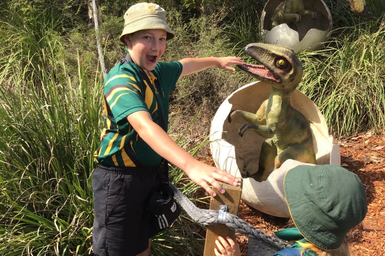 student with hand in dinosaurs mouth